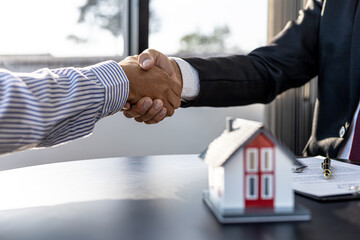 The salesperson of the housing estate in the project and the customer shake hands after...