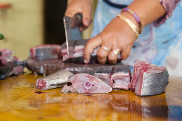 Cut tuna fish on the table of a fish seller in the fish market. The seller cut tuna into pieces.
