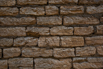 Old brown stone wall. Stone wall texture. Old bricks in old medieval wall. Exterior historical building. Village rural background. Graphic texture element.