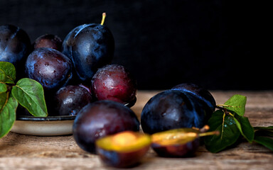Ripe plum with green leaves on rustic background. Ripe fresh organic plums.