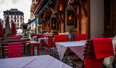Typical view of the Alpine town street with tables and chairs of cafe in France. Architecture and landmark. View of old cozy street in alpine village.