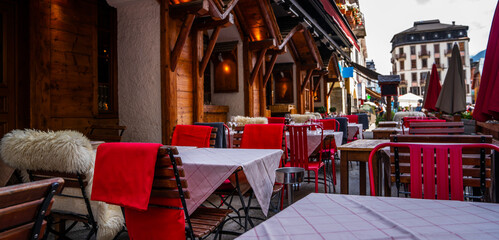 Typical view of the Alpine town street with tables and chairs of cafe in France. Architecture and landmark. View of old cozy street in alpine village.