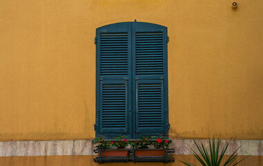 Building in italian village. Window on a yellow wall with green shutters. Building with beautiful old architecture. Architecture and landmark.