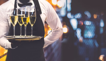 Waiter holding out glasses of sparkling wine at event.