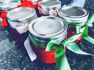 Homemade strawberry jam in jars with a ribbon wrapped around the lids.