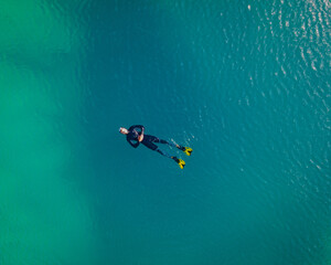 One guy snorkeling in the blue hole Izvor Cetine, Dalmatia. Aerial top down shot in April, 2021.