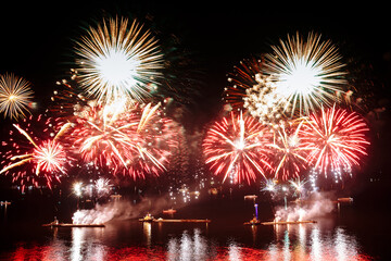 Holiday fireworks above water with reflection on the black sky background