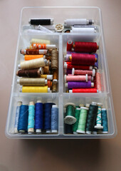 Box full of spools of threads of various colors.
