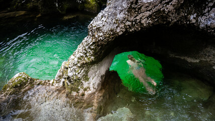 Person swimming through little Elephant, a rock formation in Mostnica river gorge in Slovenia in...