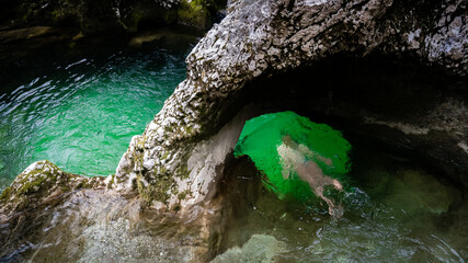 Girl swimming through little Elephant, a rock formation in Mostnica river gorge in Slovenia in the...