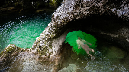 Girl swimming through little Elephant, a rock formation in Mostnica river gorge in Slovenia in the winter, ice cold water