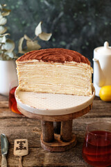 Tiramisu Crepe Cake, no decor on a wooden table. Side View.