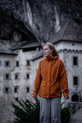 Young blond hair model in front of Predjama castle - Predjamski grad in spring, Slovenia