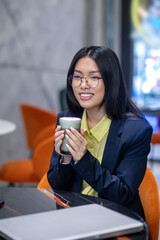 Asian business woman in the office having morning coffee