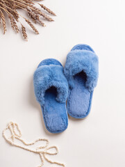 Blue women's home slippers, pearl necklace and ears of wheat. Fluffy soft slippers. Top view. Comfortable shoes for home
