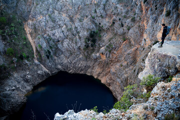Hiker looking down into the Red lake in April at Imotski, Dalmatia, Croatia