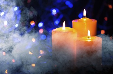 Candles over dark background. Used, almost extinguished. Burned out. Mystical smoke swirls in the dark