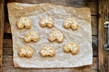 Obraz na płótnie Canvas Almond cookies with almond chips. Wooden background, parchment, top view 