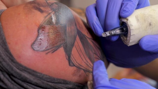 Tattoo artist make a tattoo on a man's skin with a tattoo machine. Close up