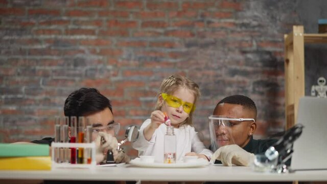 Girl with scientists do experiment with liquid and paint