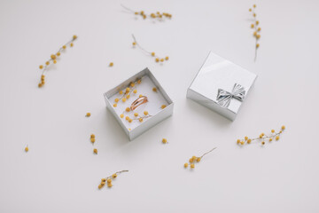 Box with golden engagement ring on flowers background, top view. Wedding, Marriage proposal concept