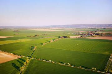 Aerial view of fresh green fields, village and farmland. Rural countryside and agriculture. Spring in April. Scenery in Saxony-Anhalt, Germany.