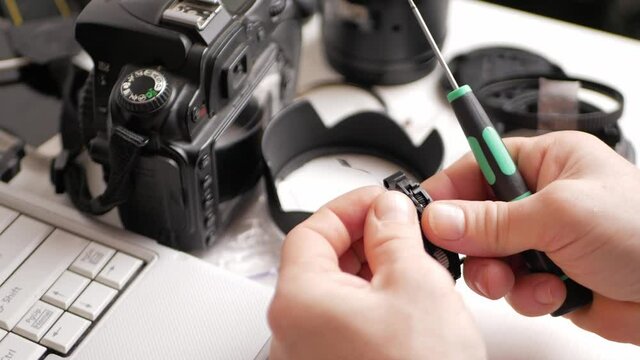 man repairs camera lens, autofocus motor, tools. screws in bolts