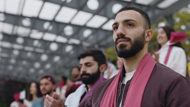 Muslim man listening anthem and applauding on soccer match