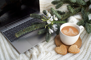 cup of cappuccino, heart-shaped cookies, laptop, spruce branches, snowdrops. romantic background, valentine's day card. congratulations on March 8. cozy scene. with love.