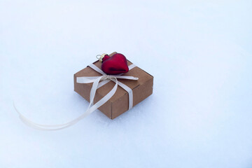 gift box and red glass heart on the snow. valentine's day card