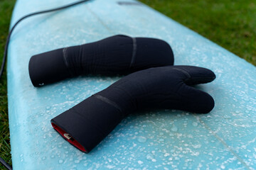 winter neoprene gloves on a wet surfboard after a cold surf session in the german north sea in...