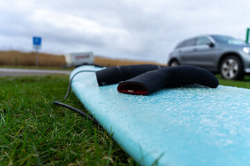 winter neoprene gloves on a wet surfboard after a cold surf session in the german north sea in...