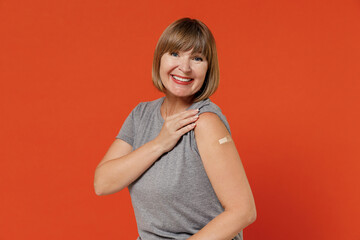 Elderly cheerful woman 50s with adhesife bandage after getting vaccine from coronavirus virus...