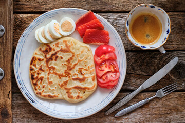Flatbread with boiled egg, salted salmon, tomato. Coffee, breakfast, top view, wooden background