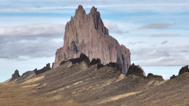 Cinematic cliff with clouds in blue sky on motion background with parallax effect. Southwest USA, New Mexico desert wanderlust travel. Nature wilderness park with epic Shiprock landscape shot on drone