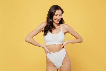 Smiling attractive young brunette woman 20s in white underwear with perfect fit body stand akimbo...