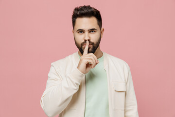 Young smiling happy secret man 20s wear trendy jacket shirt say hush be quiet with finger on lips shhh gesture isolated on plain pastel light pink background studio portrait. People lifestyle concept.