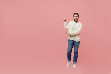 Full body young smiling happy man 20s wearing trendy jacket shirt point index fingera aside on...