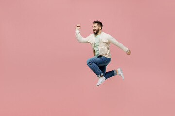 Fototapeta na wymiar Full body side view young overjoyed excited cool happy fun man 20s in trendy jacket shirt jump high run fast hurry up isolated on plain pastel light pink background studio. People lifestyle concept