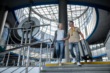 Cheerful airline passengers descending the stairs at the airport