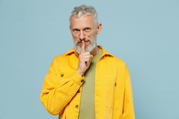 Elderly gray-haired mustache bearded man 50s in yellow shirt say hush be quiet with finger on lips...
