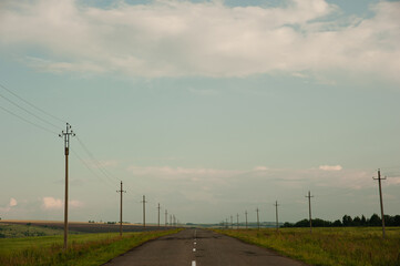 The road going beyond the horizon in the fields. Power lines along the road.