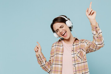 Young smiling happy cheerful student fun woman 20s wearing casual brown shirt headphones listen to music isolated on pastel plain light blue color background studio portrait. People lifestyle concept.
