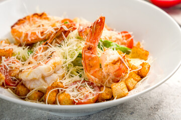 salad caesar with shrimps on white plate on grey concrete table macro close up