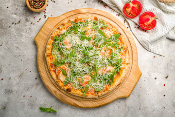 Pizza with arugula and shrimp on the board on grey concrete table top view