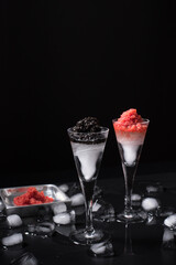Caviar de esturión negro y caviar de salmón rojo servido en copa de cóctel helada sobre fondo negro	
