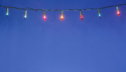 Christmas lights string on blue background with copy space..
