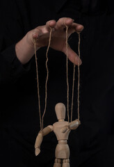 Boss hand manipulating and controling wood marionette. Master of puppet concept.