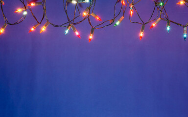 Christmas lights string on blue background with copy space..