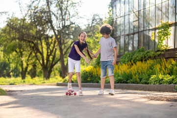 Obraz premium Concentrated boy teaching his friend to skateboard
